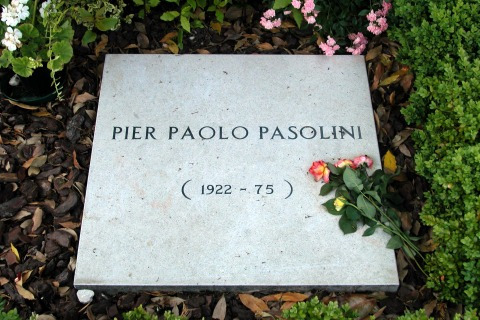 Fotografia della lapide della tomba di Pier Paolo Pasolini con alcune rose posate sopra